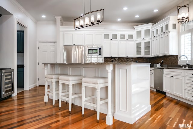 kitchen featuring beverage cooler, appliances with stainless steel finishes, ornamental molding, and an inviting chandelier