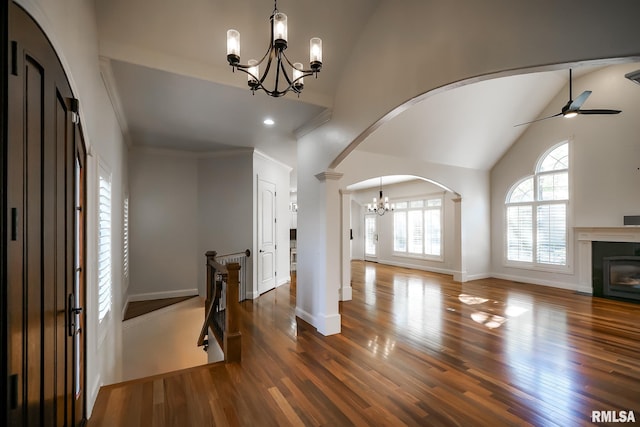 entrance foyer featuring arched walkways, a fireplace with flush hearth, high vaulted ceiling, and wood finished floors