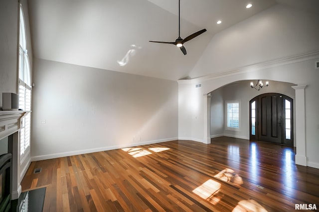 unfurnished living room with arched walkways, visible vents, high vaulted ceiling, and ceiling fan with notable chandelier
