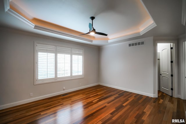 empty room with visible vents, a raised ceiling, ceiling fan, and dark wood-type flooring
