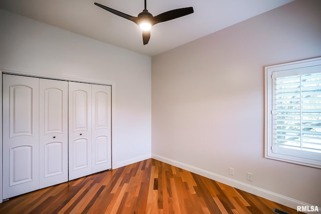 unfurnished bedroom with a closet, wood finished floors, baseboards, and a ceiling fan