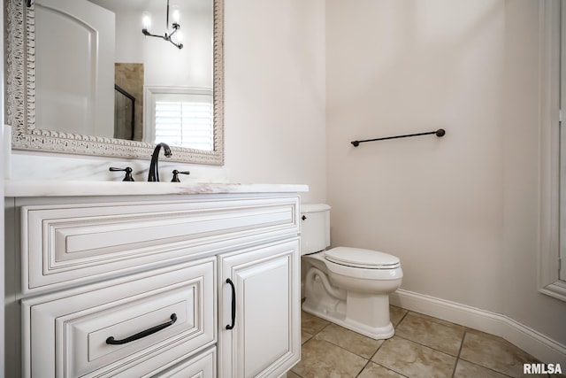 bathroom featuring toilet, a shower with door, tile patterned floors, baseboards, and vanity