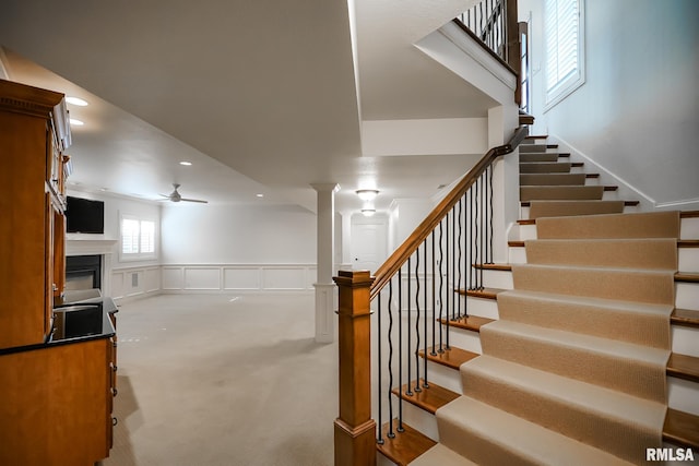 stairs featuring recessed lighting, ceiling fan, carpet floors, a fireplace, and ornate columns