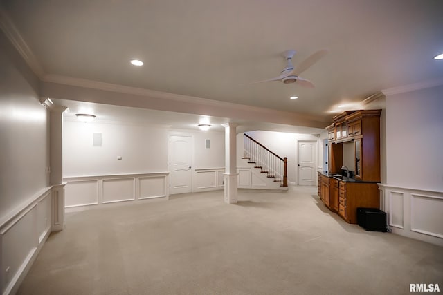 below grade area with stairway, a decorative wall, ceiling fan, light carpet, and ornamental molding