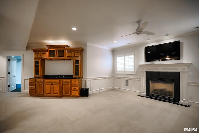 unfurnished living room with light colored carpet, ornamental molding, a decorative wall, and ceiling fan