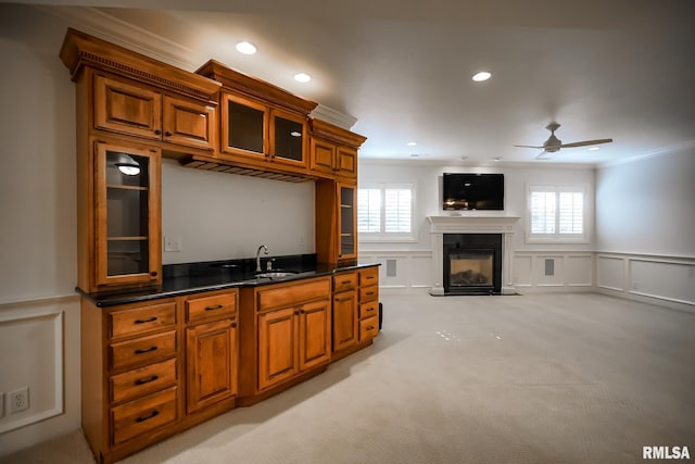 kitchen with brown cabinetry, crown molding, a decorative wall, and ceiling fan