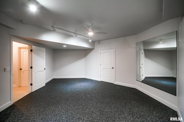 finished below grade area featuring ceiling fan, rail lighting, and baseboards