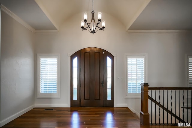 entryway with baseboards, a chandelier, vaulted ceiling, arched walkways, and wood finished floors