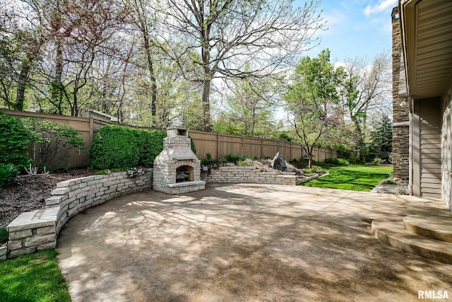 view of patio / terrace featuring an outdoor stone fireplace and a fenced backyard