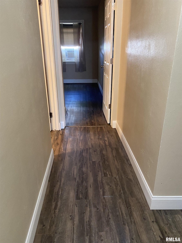 corridor with dark wood-type flooring and baseboards