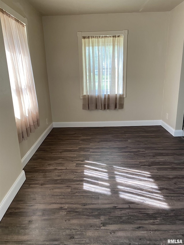 empty room featuring dark wood-style flooring and baseboards