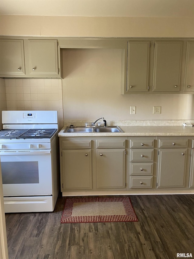 kitchen with white gas range, a sink, gray cabinets, light countertops, and dark wood-style floors