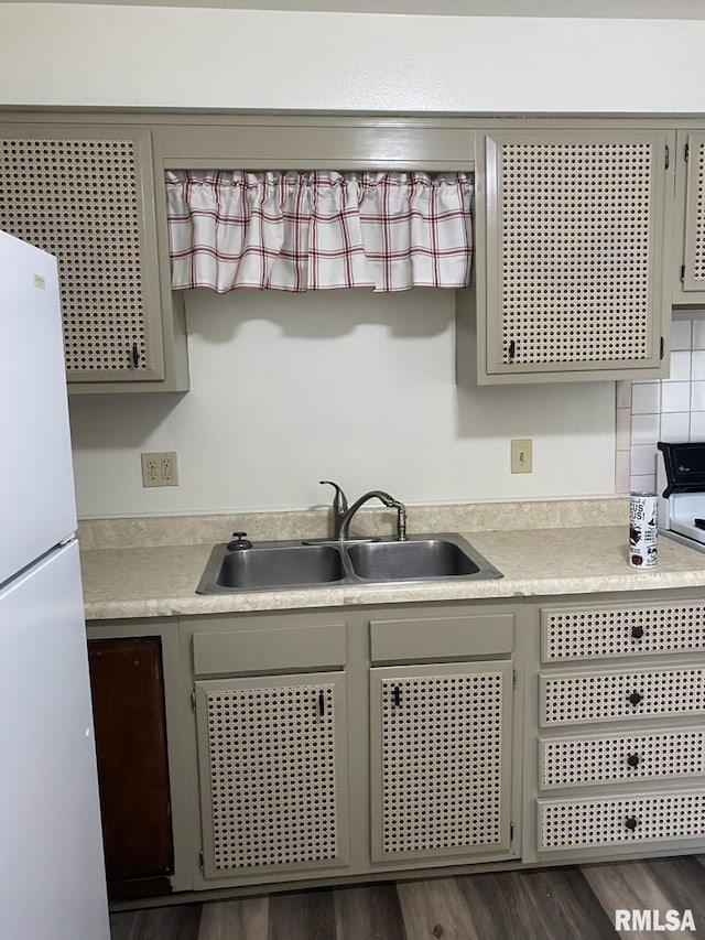 kitchen with freestanding refrigerator, light countertops, dark wood-type flooring, and a sink