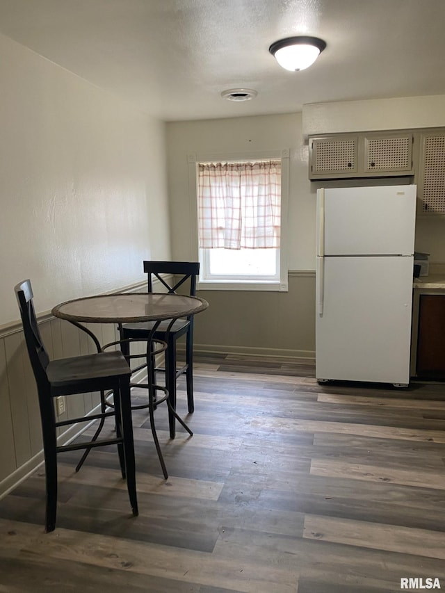 dining space featuring baseboards, dark wood-style flooring, and wainscoting