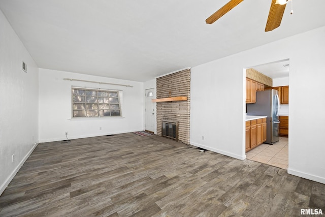 1420 N 10th St, Pekin, IL 61554 - unfurnished living room featuring wood finished floors, a fireplace, visible vents, baseboards, and ceiling fan