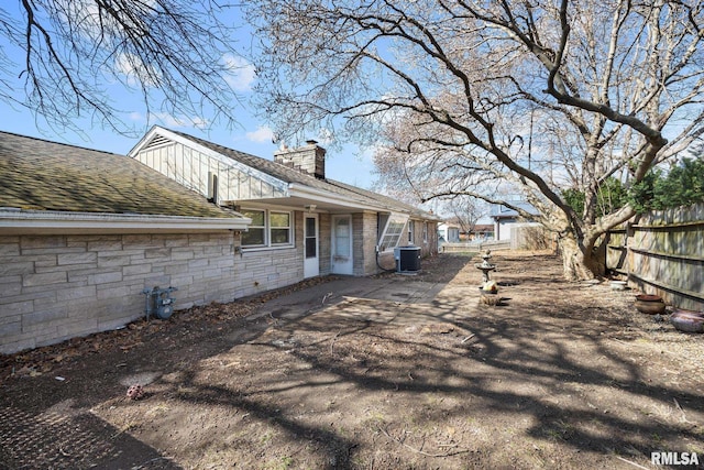 1420 N 10th St, Pekin, IL 61554 - view of side of property featuring a chimney, stone siding, central AC, and fence