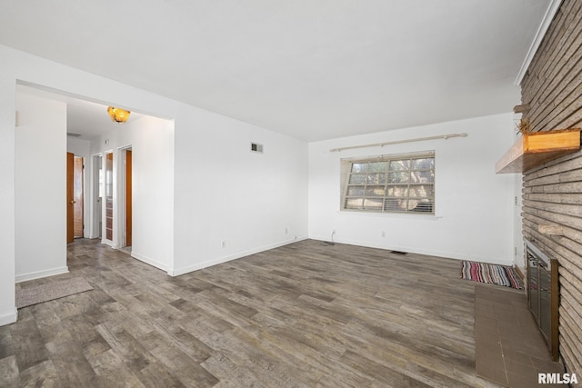 1420 N 10th St, Pekin, IL 61554 - unfurnished living room with a brick fireplace, baseboards, visible vents, and wood finished floors