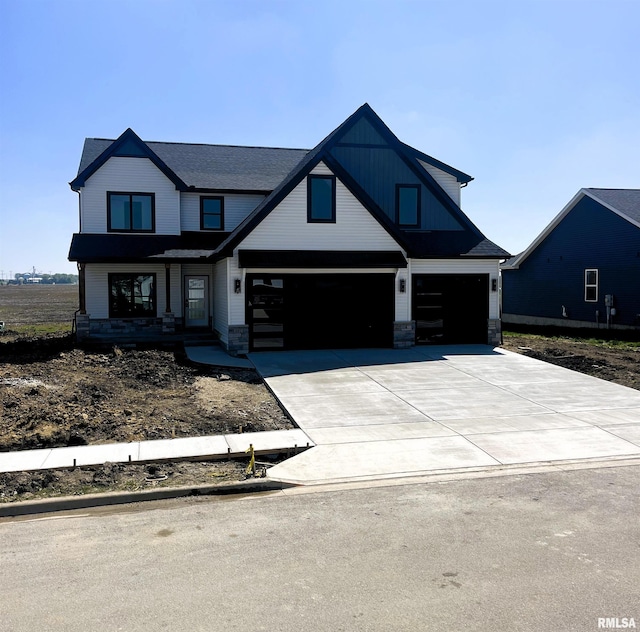 view of front of house featuring an attached garage, stone siding, and driveway