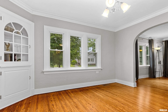 2714 W Kenwood Ave, West Peoria, IL 61604 - empty room featuring light wood-type flooring, arched walkways, baseboards, and ornamental molding