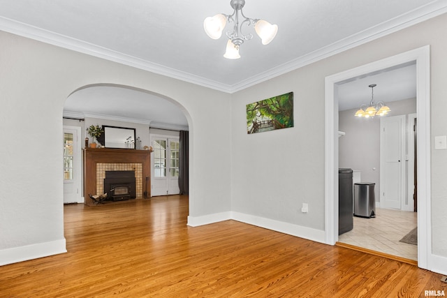 2714 W Kenwood Ave, West Peoria, IL 61604 - unfurnished living room featuring a chandelier, arched walkways, light wood finished floors, baseboards, and ornamental molding
