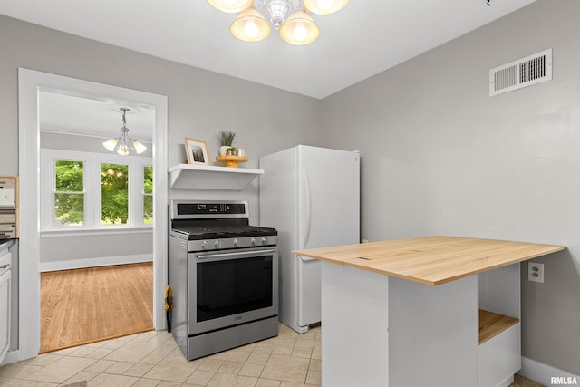 2714 W Kenwood Ave, West Peoria, IL 61604 - kitchen featuring stainless steel gas stove, a chandelier, wooden counters, freestanding refrigerator, and baseboards