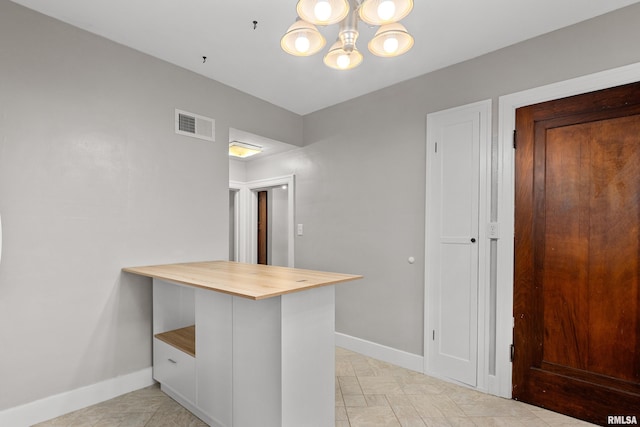 2714 W Kenwood Ave, West Peoria, IL 61604 - kitchen featuring butcher block countertops, baseboards, a chandelier, and a peninsula