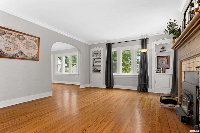 2714 W Kenwood Ave, West Peoria, IL 61604 - unfurnished living room with ornamental molding, arched walkways, baseboards, and wood finished floors