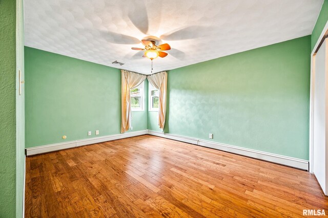 21016 N US Highway 24, Canton, IL 61520 - unfurnished room featuring baseboard heating, baseboards, visible vents, ceiling fan, and wood finished floors