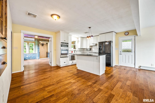 21016 N US Highway 24, Canton, IL 61520 - kitchen featuring stainless steel appliances, a healthy amount of sunlight, visible vents, dark wood finished floors, and a wall unit AC