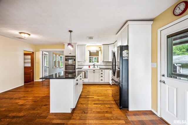 21016 N US Highway 24, Canton, IL 61520 - kitchen with white cabinets, backsplash, appliances with stainless steel finishes, a kitchen island, and dark wood-style floors
