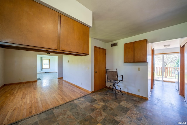 kitchen featuring baseboards, brown cabinets, and dark stone finish flooring