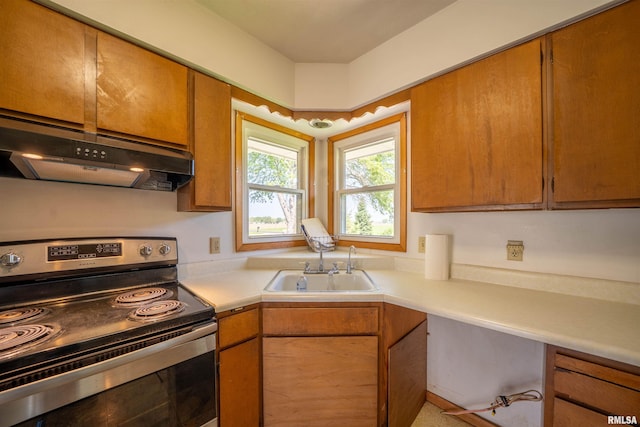 kitchen with stainless steel electric stove, under cabinet range hood, a sink, light countertops, and brown cabinets