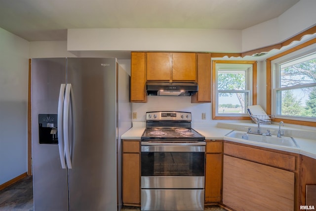 kitchen featuring appliances with stainless steel finishes, under cabinet range hood, a sink, and light countertops