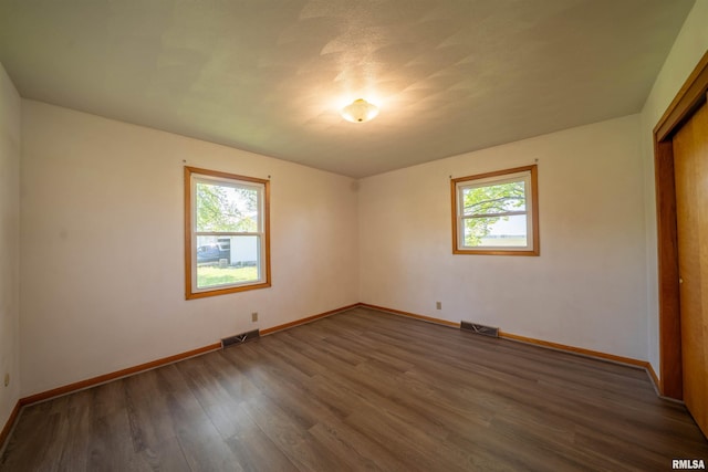 spare room featuring plenty of natural light, baseboards, and wood finished floors