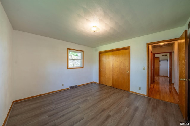 unfurnished bedroom with wood finished floors, a closet, and baseboards