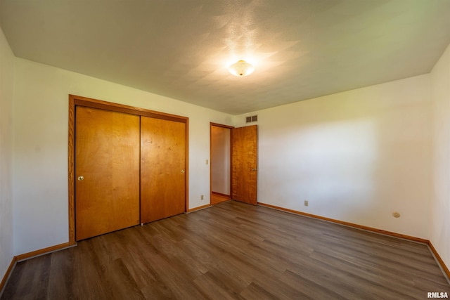 unfurnished bedroom with wood finished floors, baseboards, and a closet