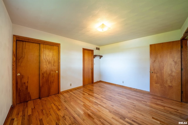 unfurnished bedroom with light wood-style flooring, a closet, and baseboards