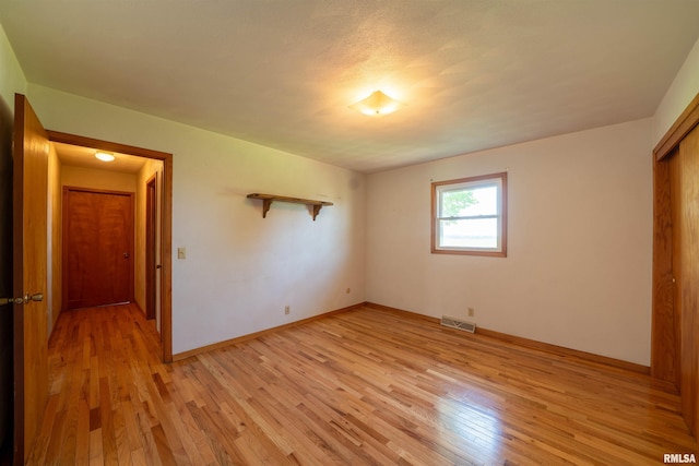 unfurnished bedroom featuring light wood-style flooring, baseboards, and a closet