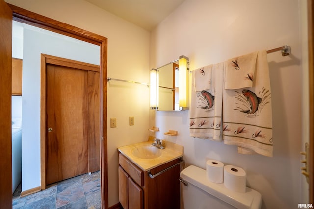 bathroom featuring toilet, stone finish floors, and vanity