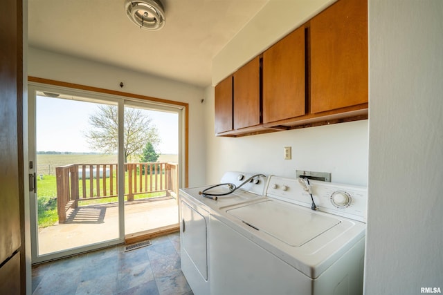 laundry area with cabinet space, independent washer and dryer, and stone finish flooring