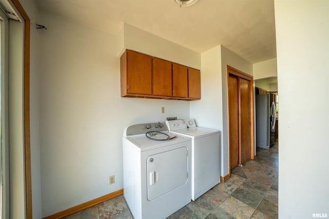 washroom featuring cabinet space, dark stone finish floors, independent washer and dryer, and baseboards