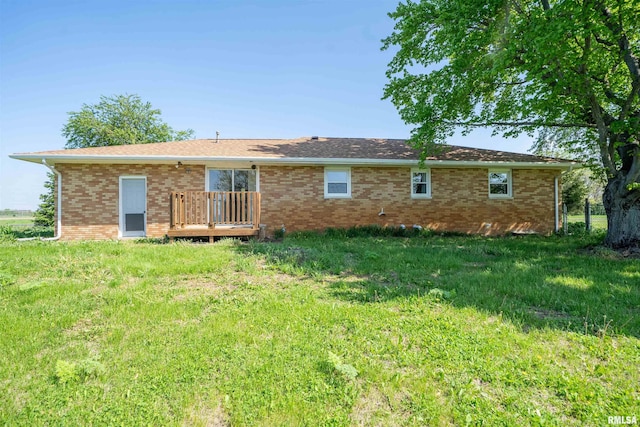 rear view of house featuring brick siding, a lawn, and a wooden deck