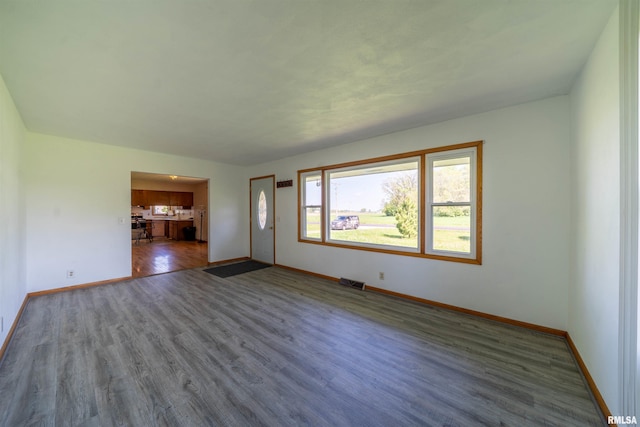 unfurnished living room with baseboards and wood finished floors
