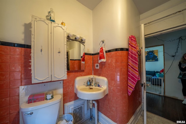 1624 W Barker Ave, Peoria, IL 61606 - bathroom featuring tile walls, wainscoting, toilet, tile patterned flooring, and a sink