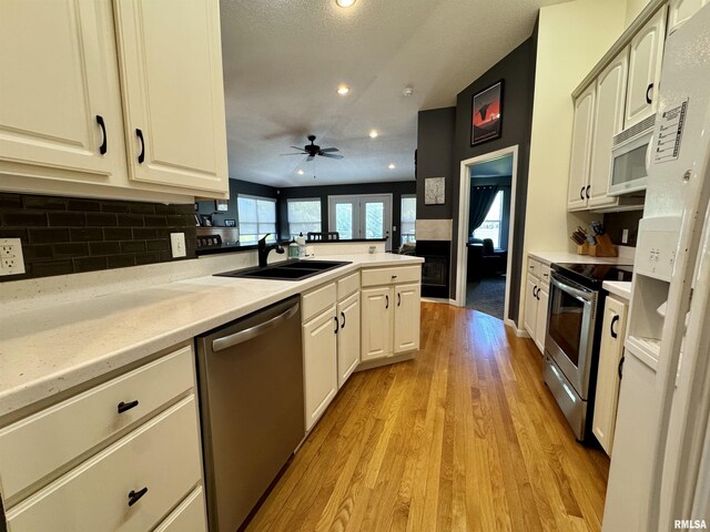 kitchen with appliances with stainless steel finishes, a sink, recessed lighting, decorative backsplash, and light wood-style floors