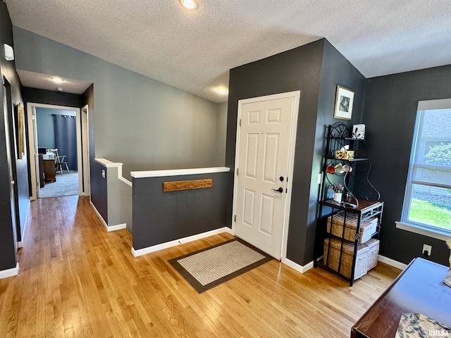 entrance foyer featuring light wood-style floors, a textured ceiling, and baseboards