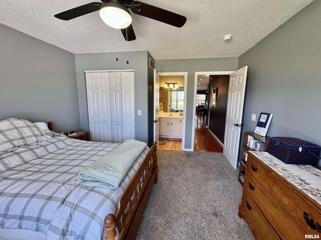 carpeted bedroom featuring a textured ceiling, a closet, ceiling fan, and connected bathroom