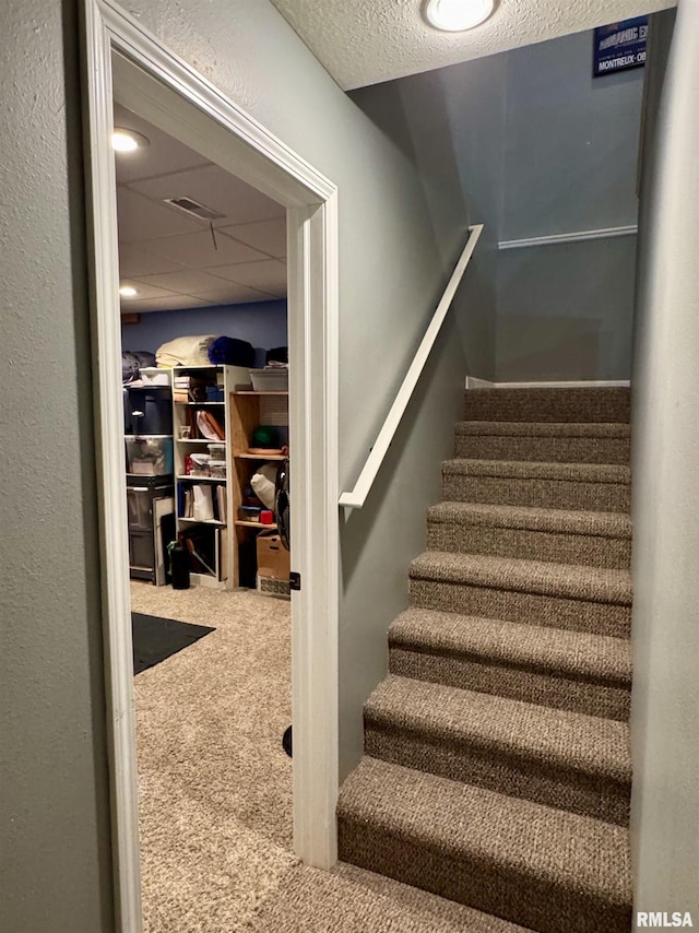 stairway with carpet and a textured ceiling