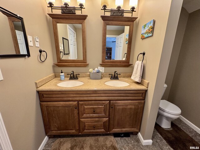 bathroom with toilet, double vanity, baseboards, and tile patterned floors