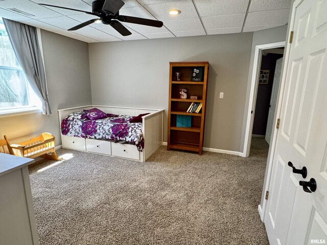 bedroom featuring carpet flooring, a drop ceiling, a ceiling fan, and baseboards